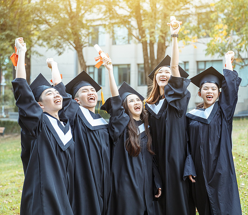 在大学校园里，快乐的学生们穿着毕业礼服，拿着毕业证书