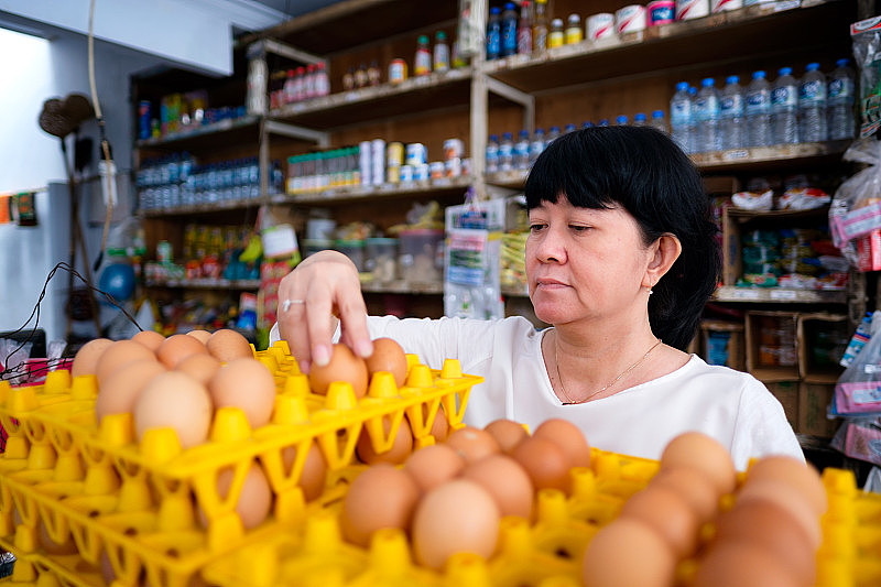 亚洲印尼妇女在当地小型家庭经营的商店里安排鸡蛋，当地称为warung。有选择性的重点。