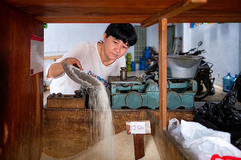 亚洲印尼妇女在当地一个小型家庭经营的商店里卖大米，当地称为warung。有选择性的重点。