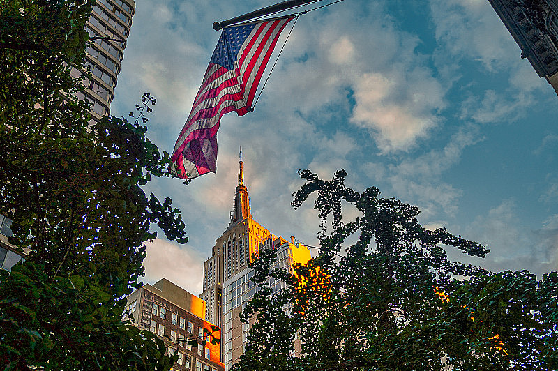 低透视图照明的帝国大厦在纽约和悬挂美国星条旗。