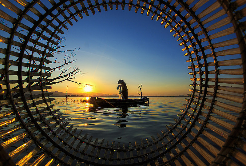 泰国春武里省邦普拉水库的渔民在日出时用渔网捕鱼的剪影。