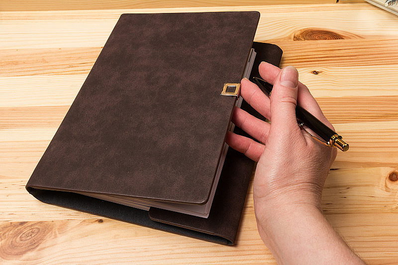 皮革装订的商业笔记本与帕克笔在木制的背景。经营理念