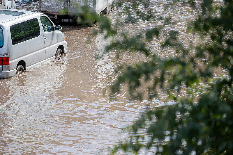 汽车在大雨中行驶在被水淹没的道路上