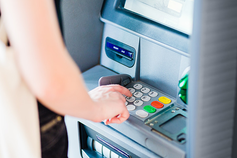 使用ATM机输入密码取钱的人。特写镜头。