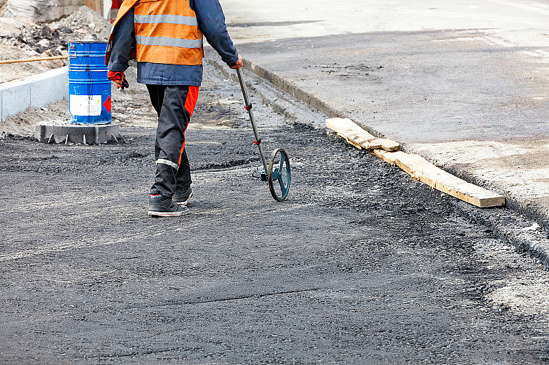 道路服务工程师用电子测量轮测量沥青路面所需的面积。