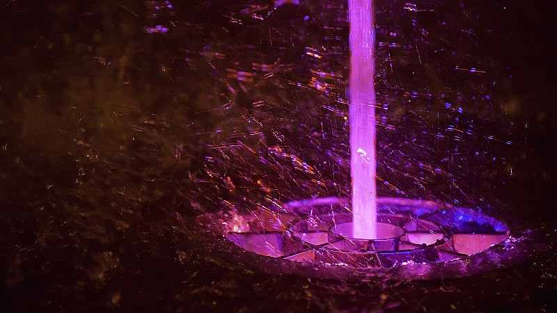 喷溅着五彩缤纷的喷泉。水被照亮，以不同的颜色落在一个喷泉，改变其水的颜色在夜晚。