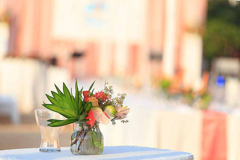 婚礼桌上的玻璃花瓶里有一束花。婚礼装饰用玻璃花瓶放在桌上。