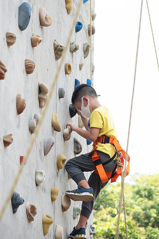 一个小男孩在攀岩墙上爬