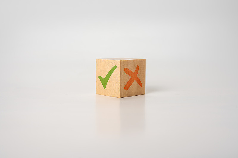 在木制立方体上打勾和交叉标记x。带有绿色勾号和红色x的木块。积极或消极决策的概念，或批准或拒绝的选择。