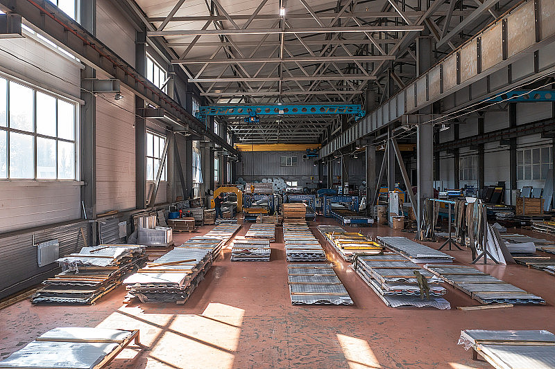 工业厂房车间或仓库内部用于生产金属屋面瓦。生产屋面上的自动化输送带及流水线设备