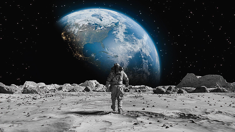 勇敢的宇航员穿着宇航服在月球上自信地走向地球。覆盖在岩石。第一位登上月球表面的宇航员。人类的重大时刻。先进技术，太空探索/旅行，殖民概念。