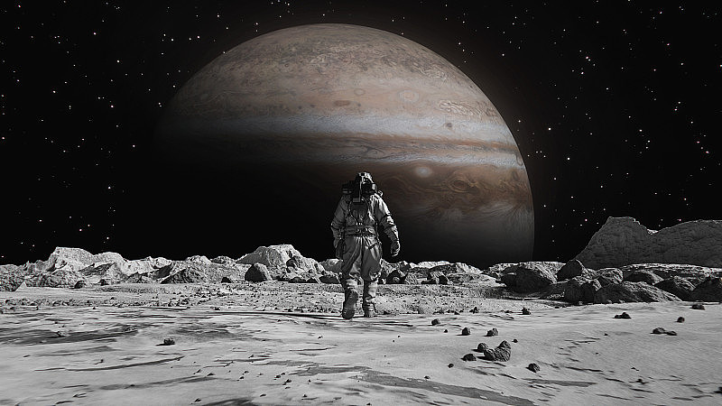 勇敢的宇航员穿着宇航服在月球上自信地走向布满岩石的木星。第一位登上月球表面的宇航员。人类的重大时刻。先进技术，太空探索/旅行，殖民概念。
