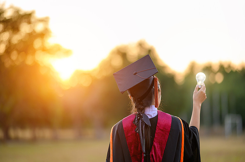 毕业生戴着黑帽子拿着大学毕业证书，向概念教育祝贺。毕业典礼，祝贺大学毕业生。