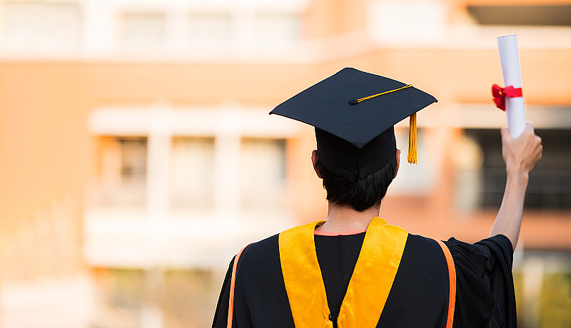 毕业生戴着黑帽子拿着大学毕业证书，向概念教育祝贺。毕业典礼，祝贺大学毕业生。