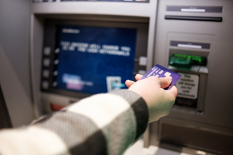 女性手插入信用卡在取款机。