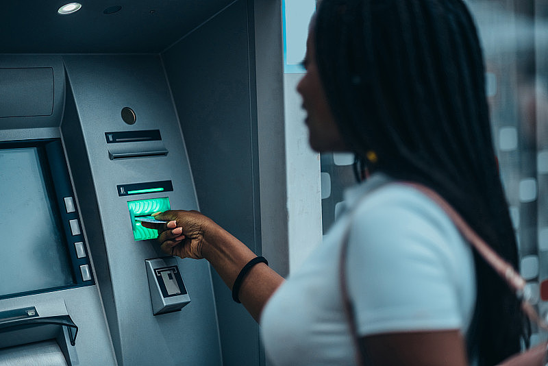 漂亮的非裔美国女人用自动取款机和信用卡