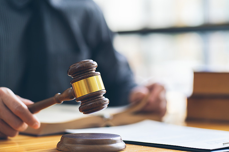男律师或法官在法庭上处理合同文件，法律书籍和木槌，律师事务所的司法律师，法律和法律服务的概念。