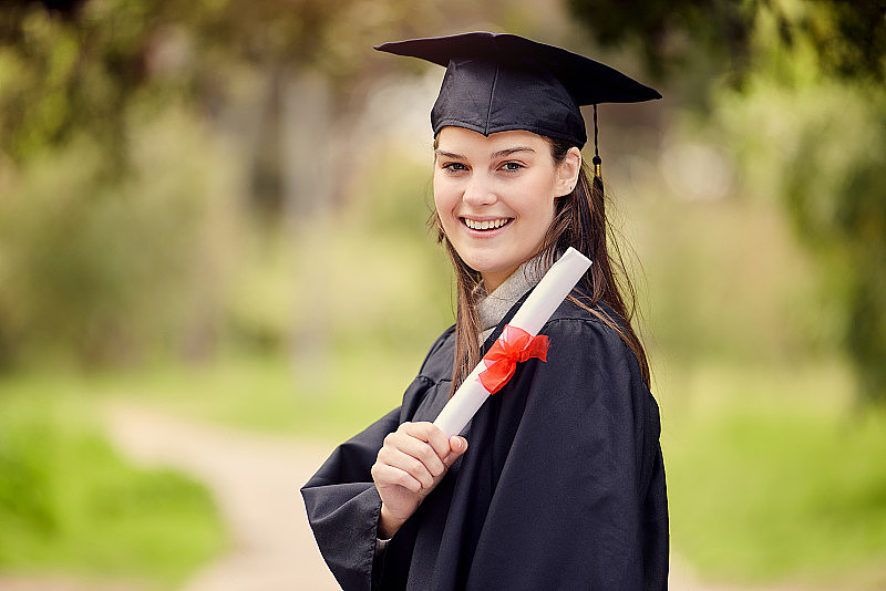 一名年轻女子在毕业典礼上手持毕业证的肖像
