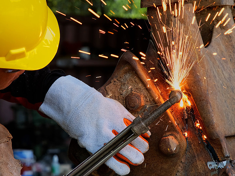工人用气枪切割钢材。人用丙烷和氧气切割钢材。使用燃料气体和氧气焊接和切割金属的工艺。