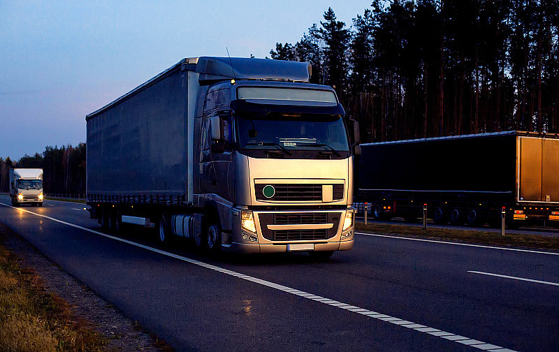 一辆漂亮的卡车和一辆拖车，映衬着黄昏前的夕阳。卡车司机工作和休息制度的概念。违例罚款