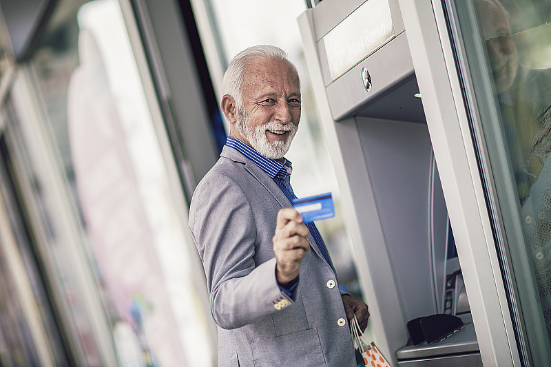 老人用信用卡使用自动取款机。