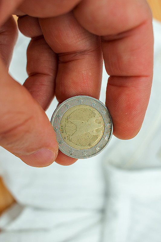 一枚来自德国的两欧元硬币夹在我的手指间