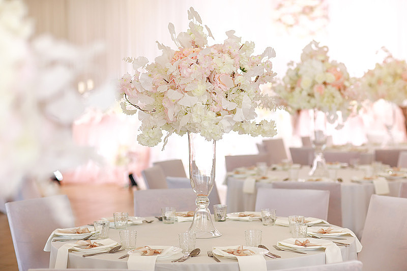 喜庆的婚礼装饰。在婚礼当天，餐桌上的玻璃花瓶里插着美丽新鲜的白色和粉色花朵。高质量的照片