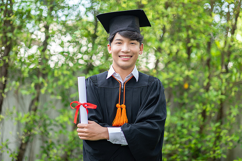 毕业典礼上，亚裔毕业生举起双手，拿着证书庆祝，如此骄傲和幸福。在毕业的日子祝贺同学们。教育成功的概念