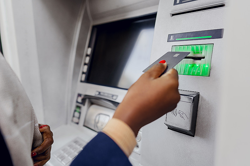 年轻的非洲妇女在自动取款机上取钱