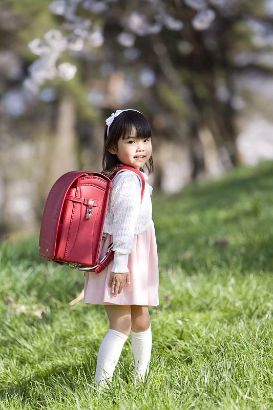 新小学生的笑脸静静地站在草坪上