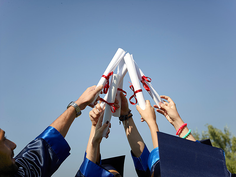 一群大学毕业生举着文凭在空中