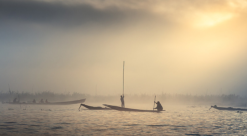 在雾中捕鱼的渔民的剪影