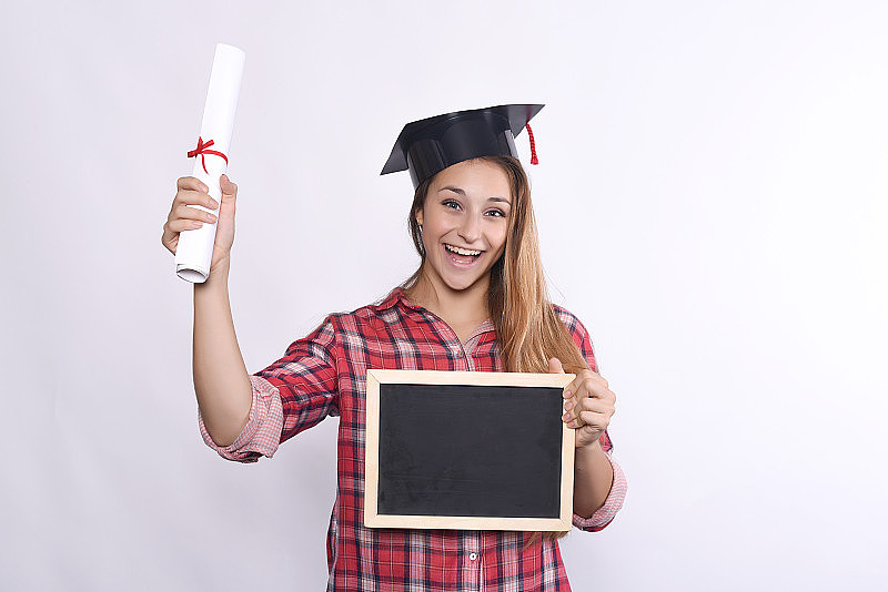 年轻的女孩毕业了黑板和文凭。