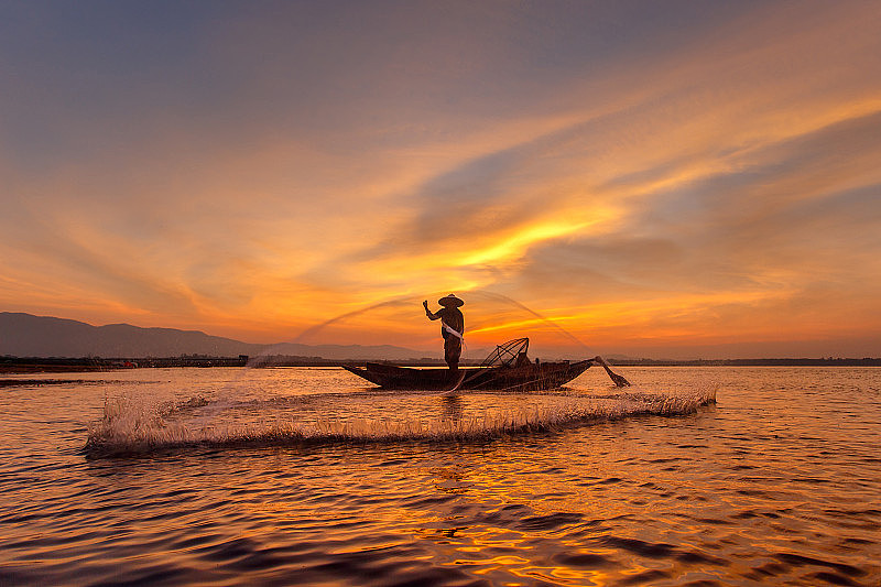湖面上传统渔民撒网捕鱼的剪影