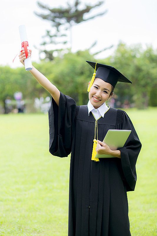 女研究生头戴毕业帽，身穿毕业服，手拿毕业证
