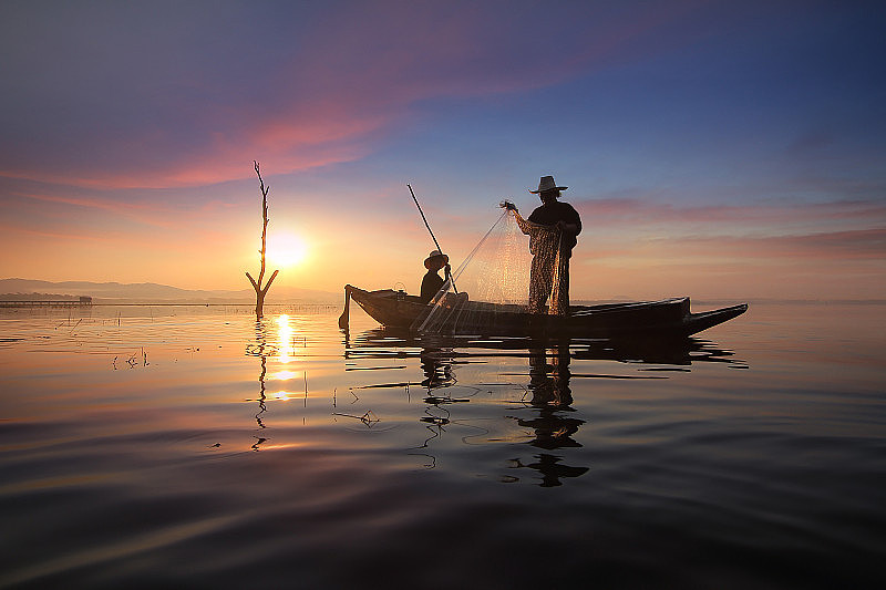 渔民用渔网捕鱼的剪影