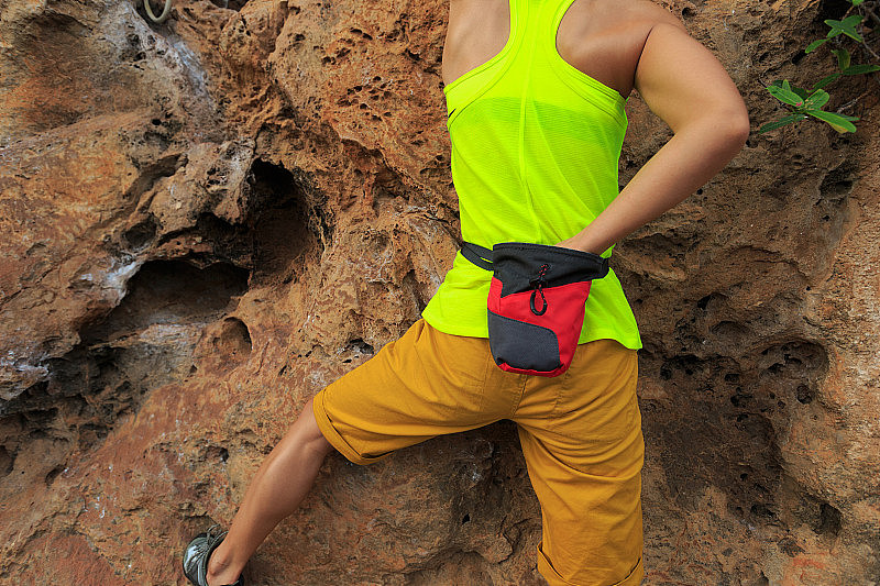 自由的独自女性攀岩者攀登海边悬崖