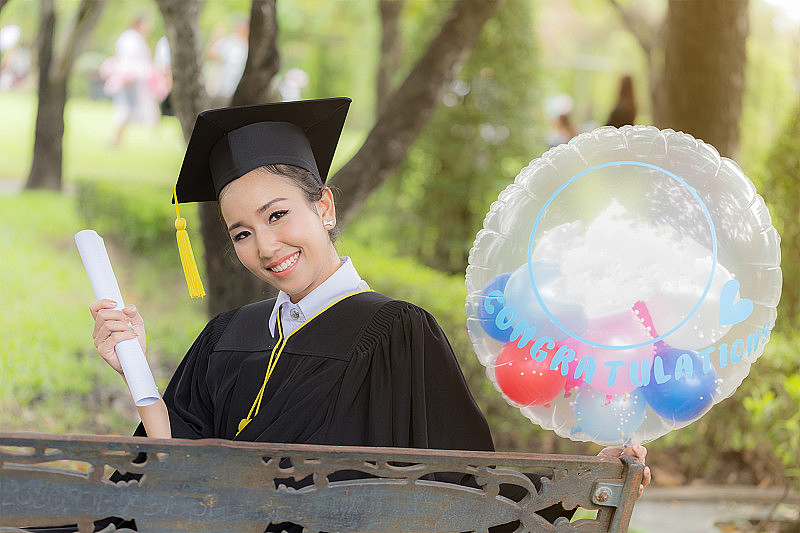 毕业庆祝，手里拿着气球和证书，镜头光晕效果