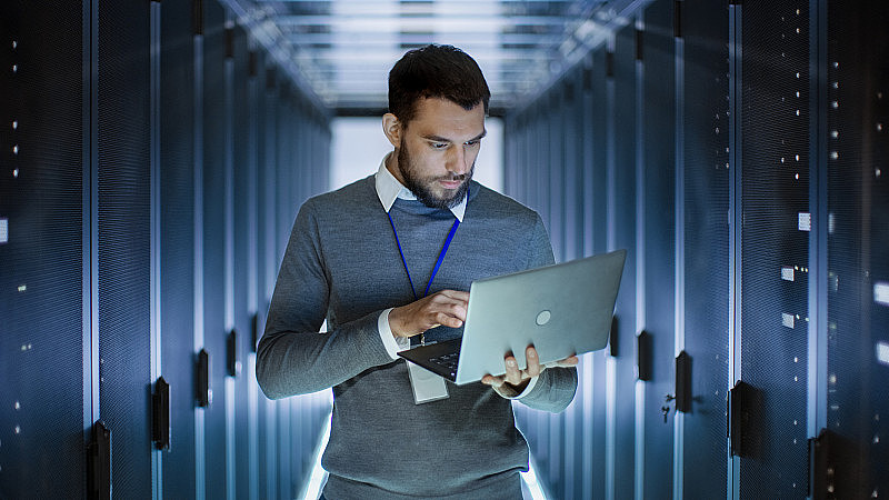男性服务器工程师在大型数据中心的笔记本电脑上工作。