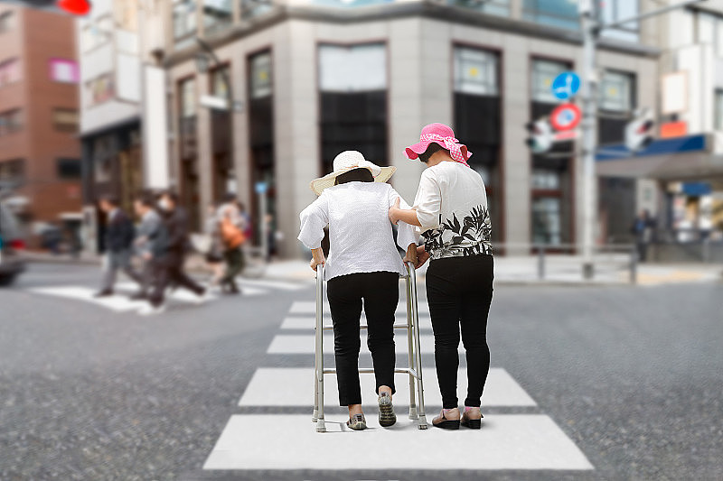 女儿照顾在市区街道上行走的老妇人。