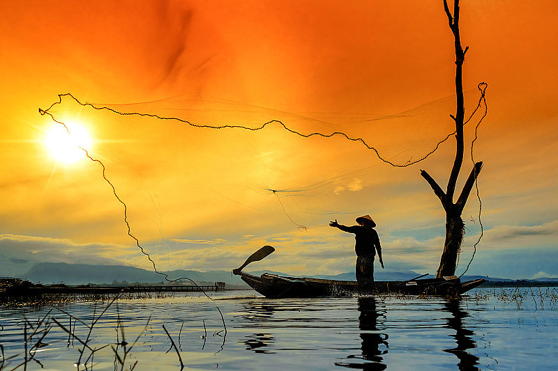 渔民捕鱼网捕获在湖上的河流日落泰国