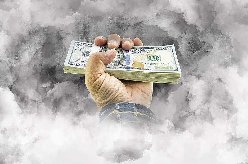 一个手握美元的男人对金钱烟概念的经济信心