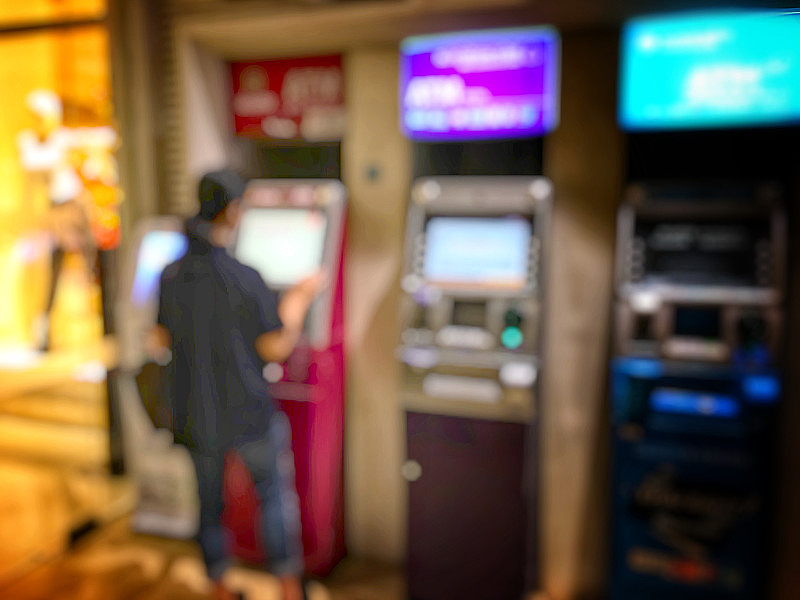 模糊的图像，人们排队使用银行或ATM机(自动取款机)在城市夜间存款，可以说明人们使用ATM机