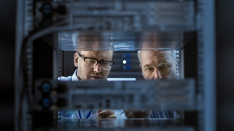 2名服务器工程师在服务器机架安装硬件。他们在大型现代数据中心工作。