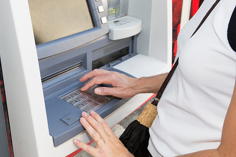 一个女人用信用卡在银行提现点取钱在城市里，户外生活