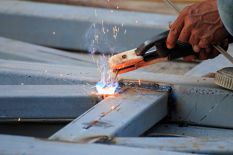 亚洲工人在焊接钢材时产生火花