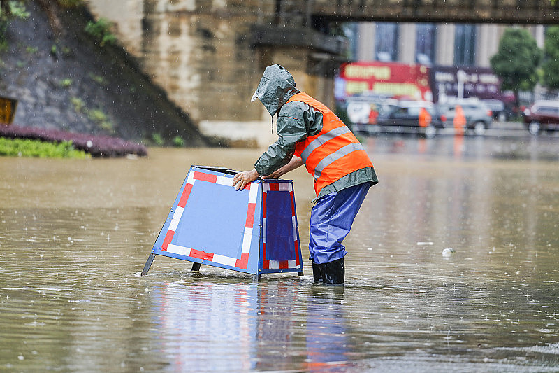 在被暴风雨淹没的街道上，市政工作人员放置了提醒物，防止行人进入下水道。