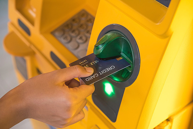 用信用卡手插入银行自动取款机。一个用信用卡atm机取钱的人
